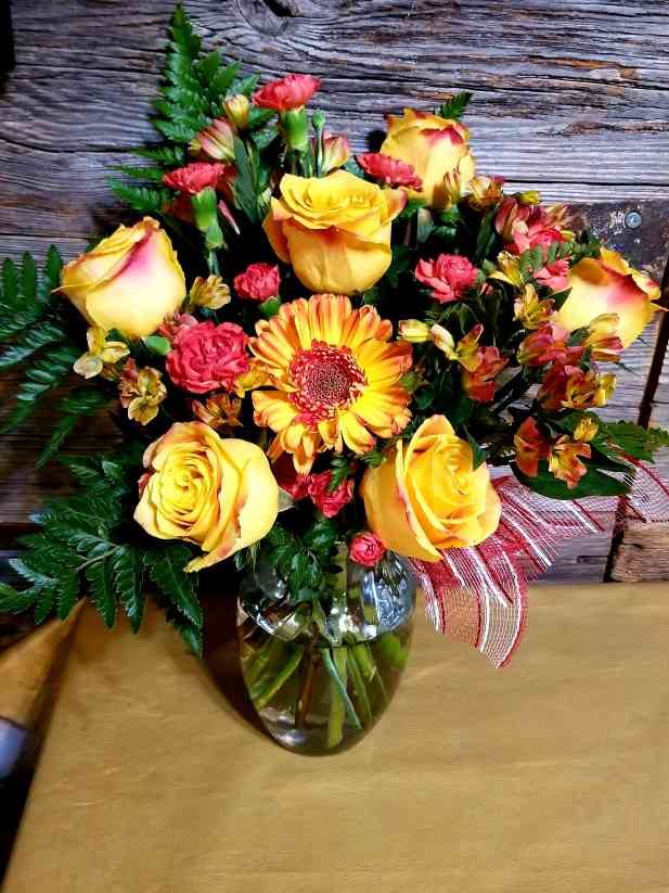 Yellow, red, and pink roses and flowers with greenery.