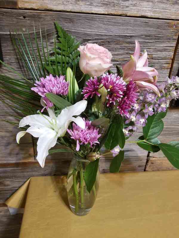 Pale pink, white, and light purple flowers with greenery.